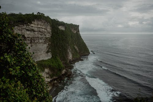 Green and Brown Coastal Cliff Under Dark Clouds