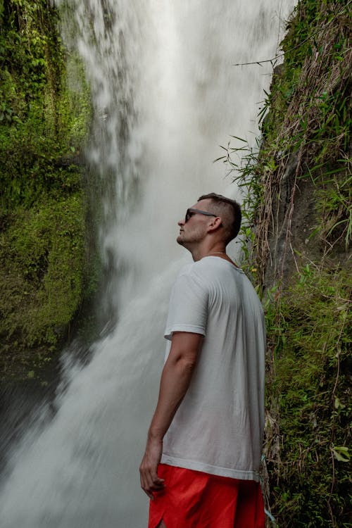 A Man in White Shirt Standing Near the Waterfalls