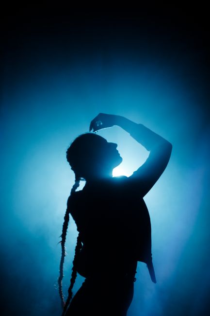 A dramatic silhouette of a woman posing elegantly against a blue backlight, creating a striking visual effect.