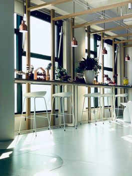 Contemporary kitchen space with stools and large windows.