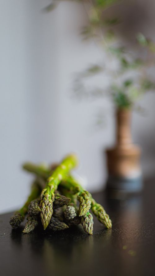 Free A close-up view of fresh asparagus spears on a dark surface with a blurred background. Stock Photo