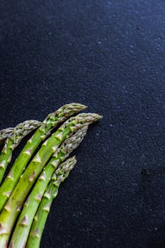 Close-up of fresh green asparagus spears on a textured dark background.