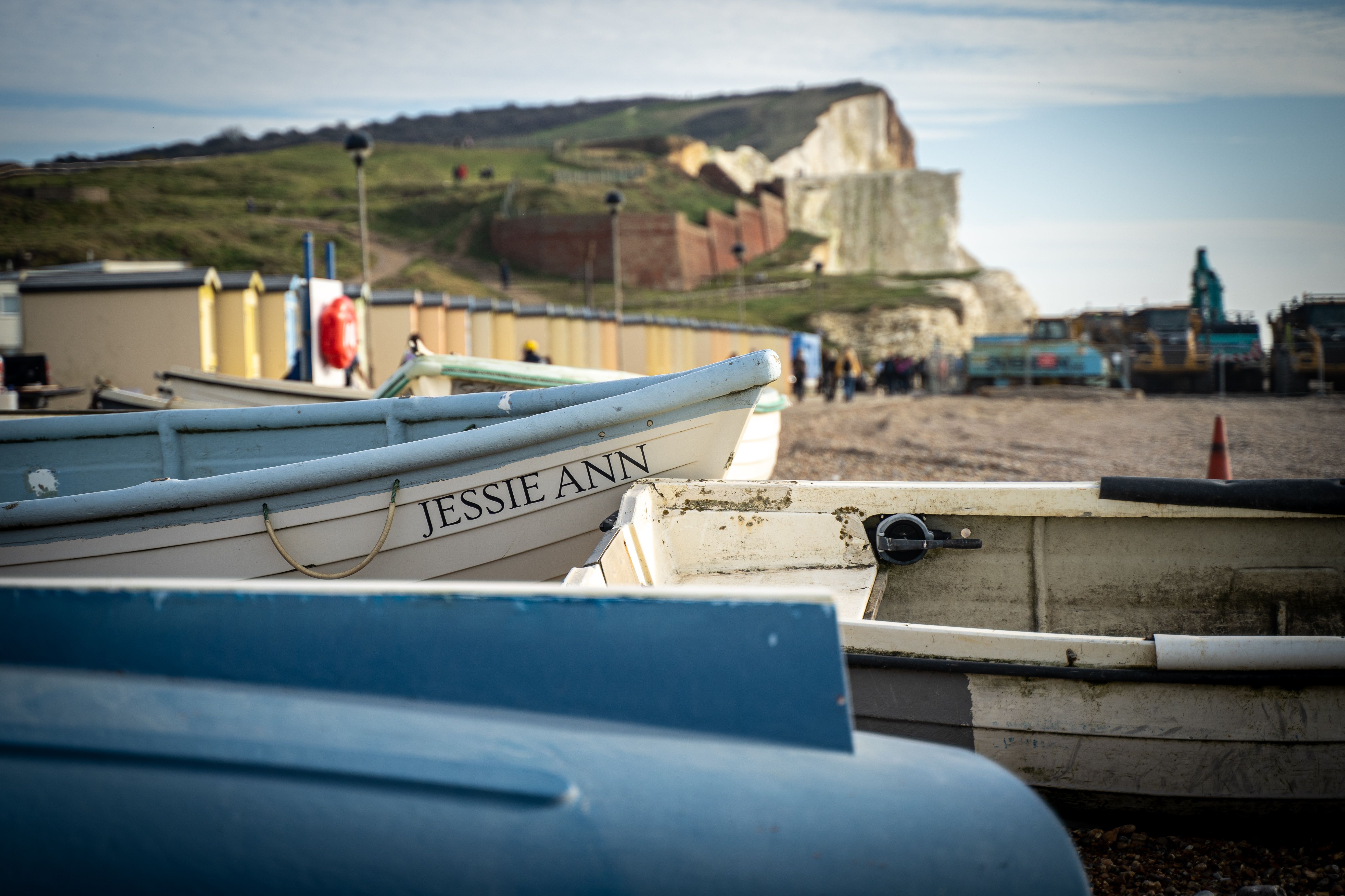 Boats at Seaford beach in England with iconic chalk cliffs in the background.