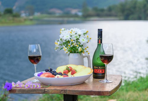 Wine and Food on a Table by a Lake 