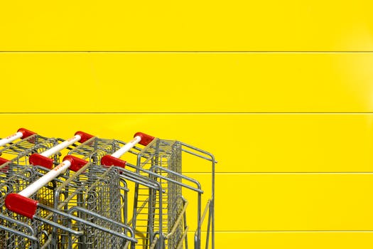 Shopping carts aligned neatly with vibrant yellow backdrop, ideal for retail and shopping themes.
