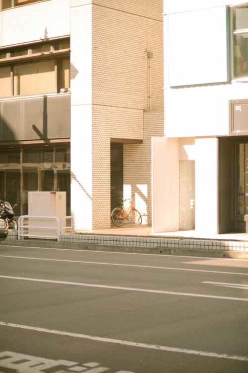 Free A quiet urban street corner with modern buildings and a bicycle in warm sunlight. Stock Photo