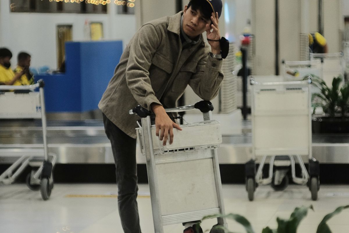 Passenger pushing a baggage trolley through a terminal