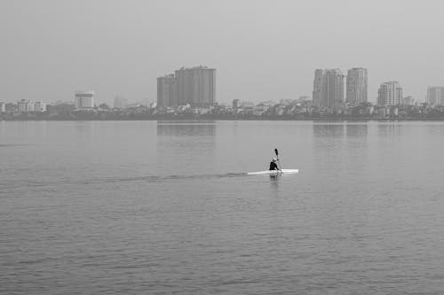 A Grayscale Photo of a Person Riding a Boat on the Sea