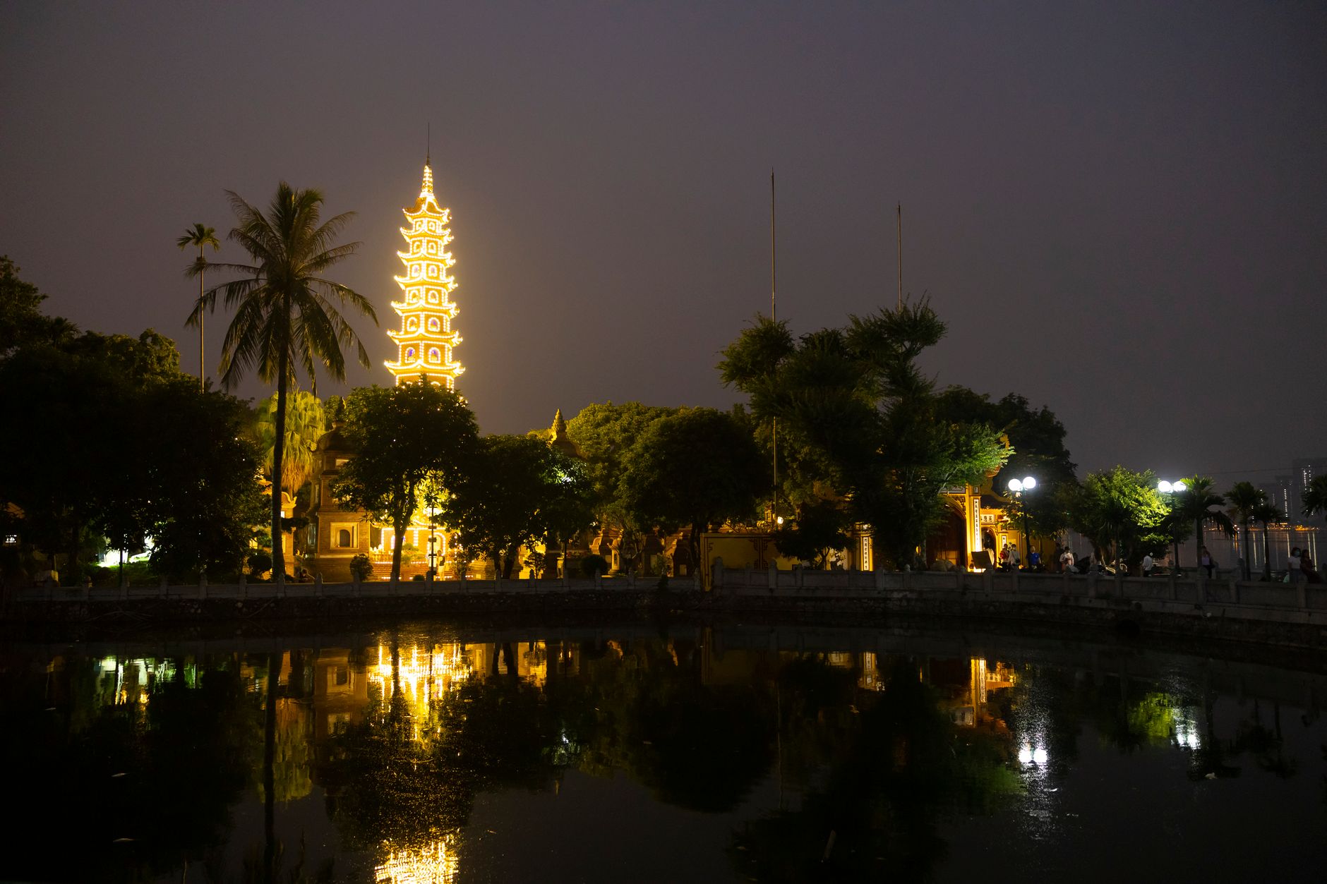 Scenic view of a beautifully lit pagoda reflecting in a pond at night.