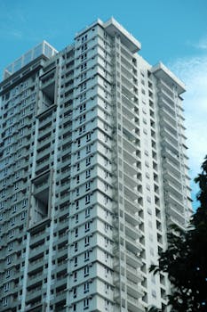 A towering residential apartment building reaching into a clear blue sky.