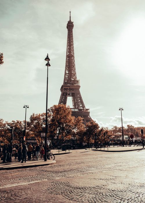 Free Eiffel Tower in Paris with a crowd enjoying a sunny autumn day and vibrant foliage. Stock Photo