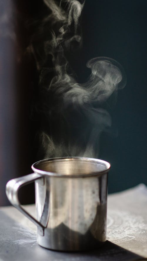 Taza De Acero Inoxidable Gris Llena De Líquido Caliente Sobre Una Superficie Marrón