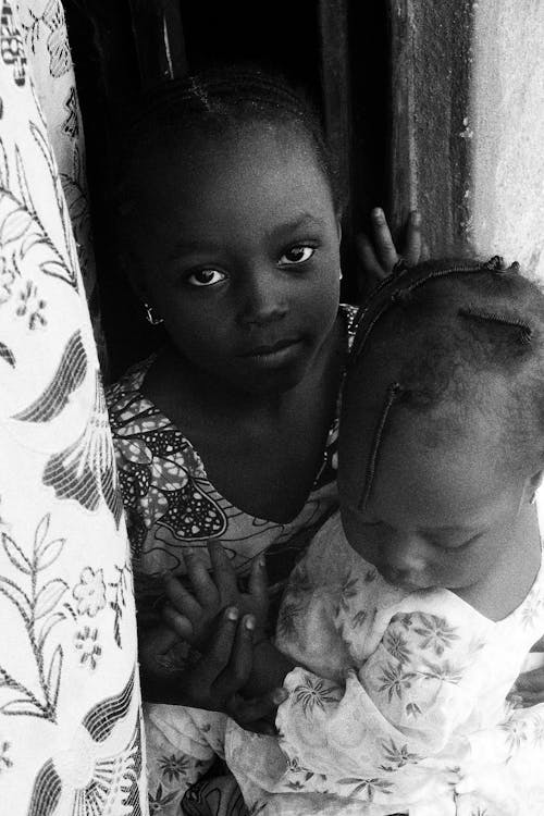  Grayscale Photo of a Girl Holding Her Sister 