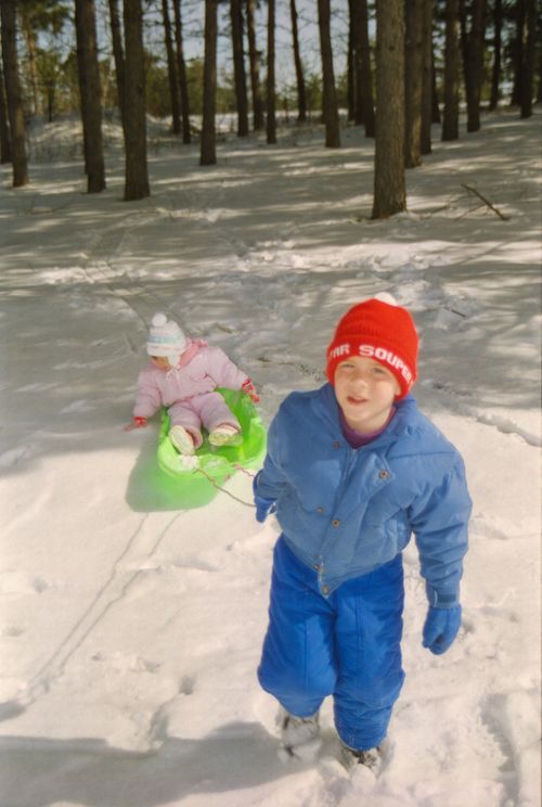 Free Children sledding in a snowy Rochester forest, having fun in winter outdoors. Stock Photo