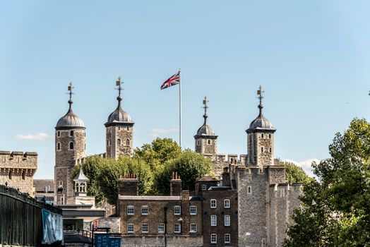 View of the Tower of London with the Union Jack flying, showcasing historic architecture.
