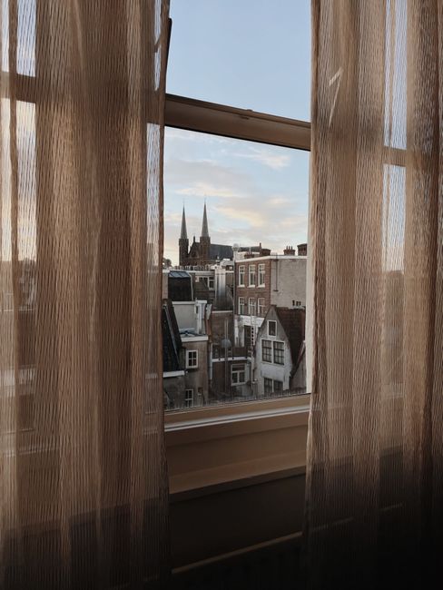 Urban skyline seen through a window curtain at dusk.