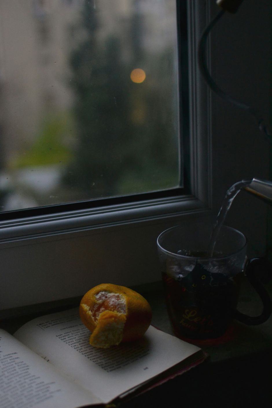 A serene scene of tea preparation with a book and scone by a window, perfect for relaxing moments.