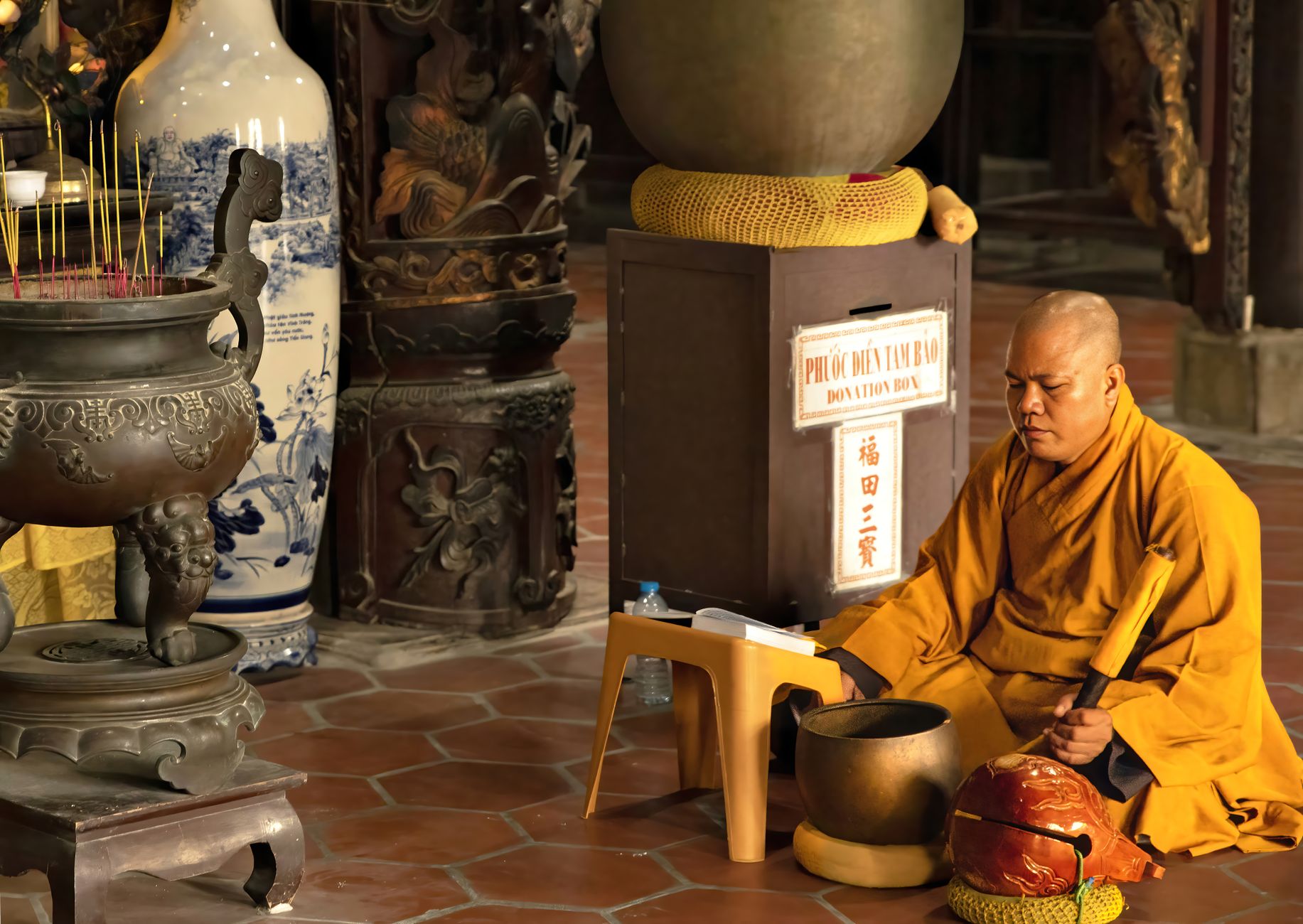 A monk in deep meditation inside a traditional temple, surrounded by sacred objects and offerings.