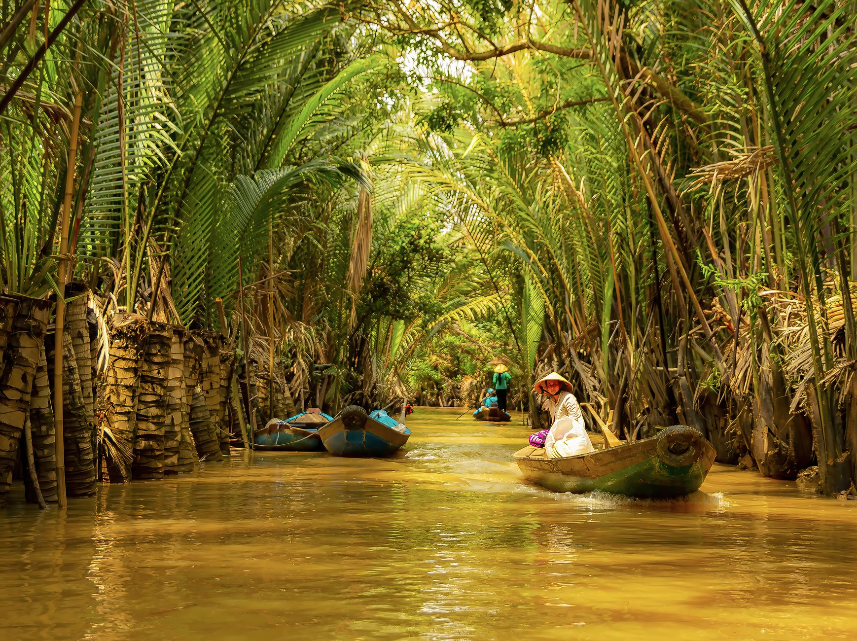 A peaceful journey down a tropical canal with boats and lush greenery.