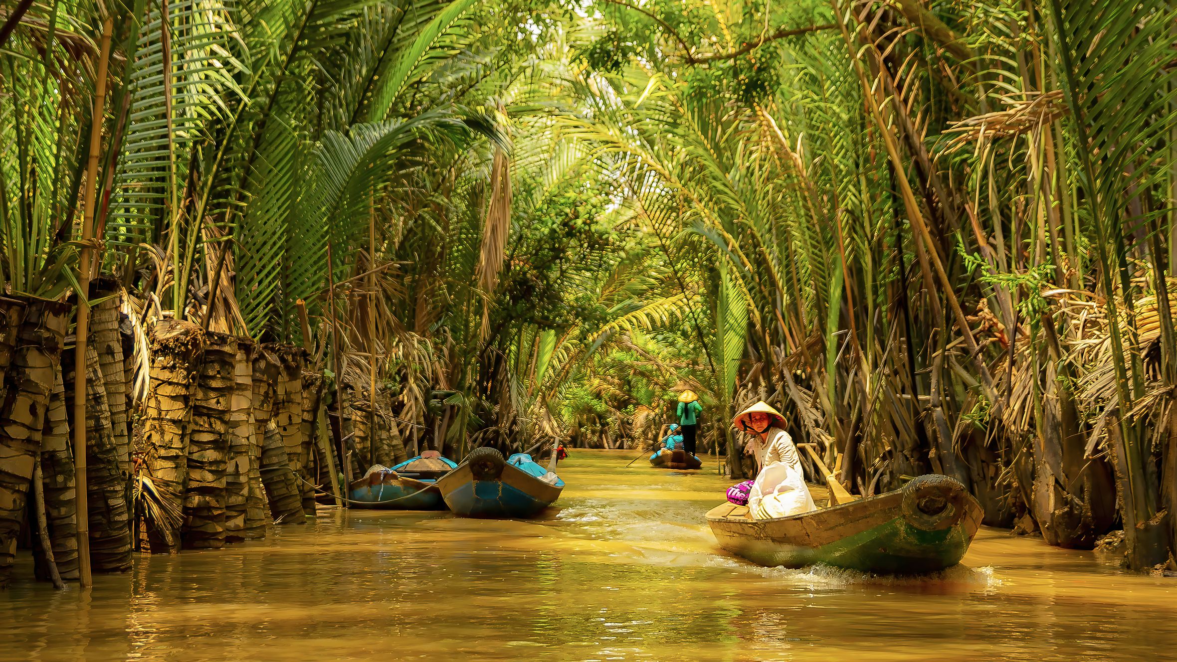 A peaceful journey down a tropical canal with boats and lush greenery.