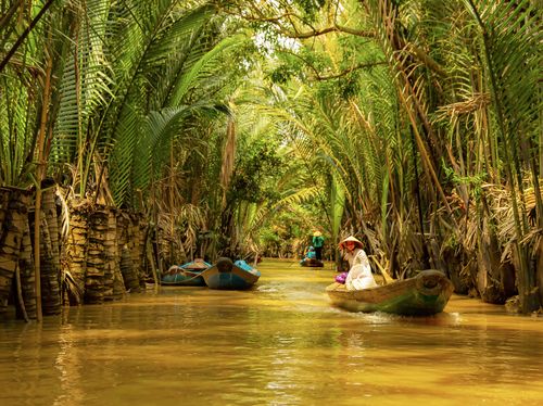 Free A peaceful journey down a tropical canal with boats and lush greenery. Stock Photo