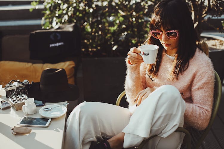 Woman Sitting By Cafe Table Drinking Tea