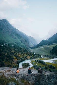 Breathtaking mountain valley with a winding river and travelers enjoying the tranquil landscape.