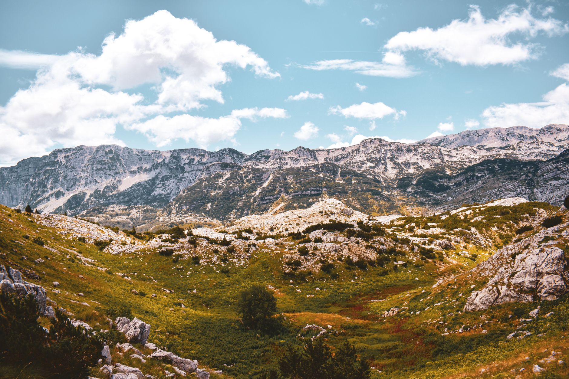 Breathtaking view of rugged mountains and grasslands under a vibrant sky in Bosnia and Herzegovina.