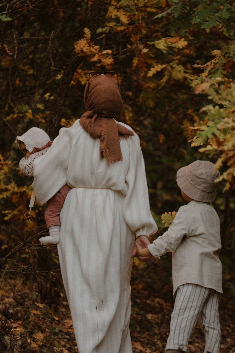 Woman With Her Children Walking In The Forest 