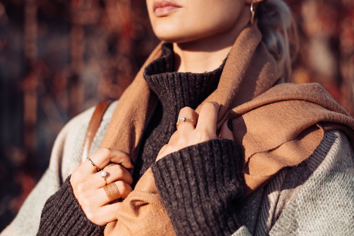 Vrouw in een bruine gebreide sjaal over een beige jas