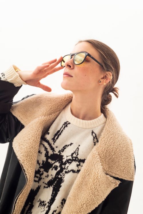 Free Portrait of a fashionable woman posing in a shearling jacket and eyeglasses on a white background. Stock Photo