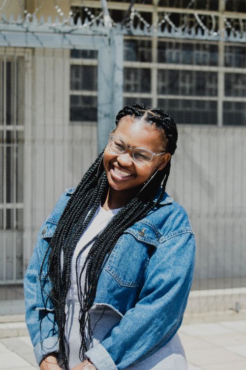 Free Portrait of a black woman with braids and eyeglasses, smiling brightly outdoors. Stock Photo