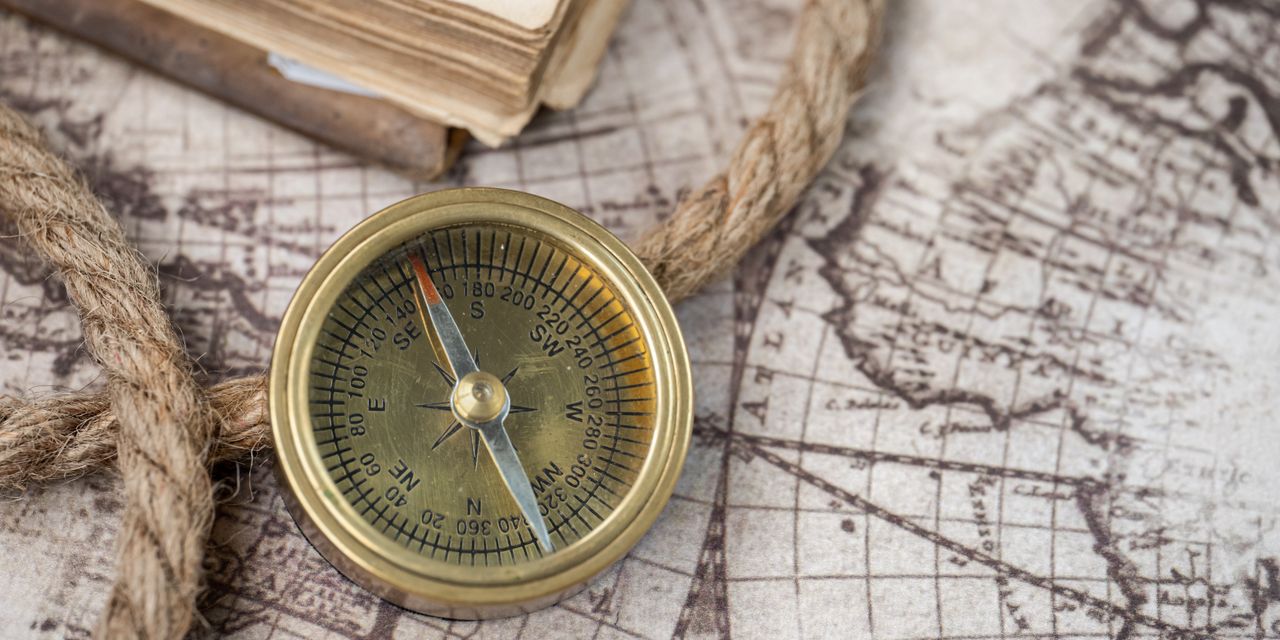 A close-up of a vintage compass on an antique world map, depicting navigation history.