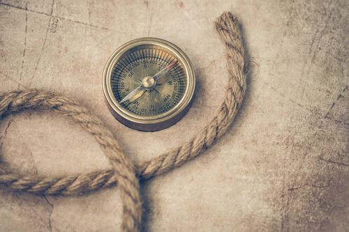 Free An old compass and rope resting on a vintage map, evoking adventure and navigation. Stock Photo