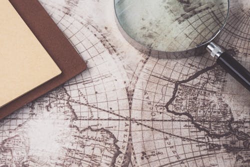 Magnifying Glass and Notebook on a Copy of an Old World Map