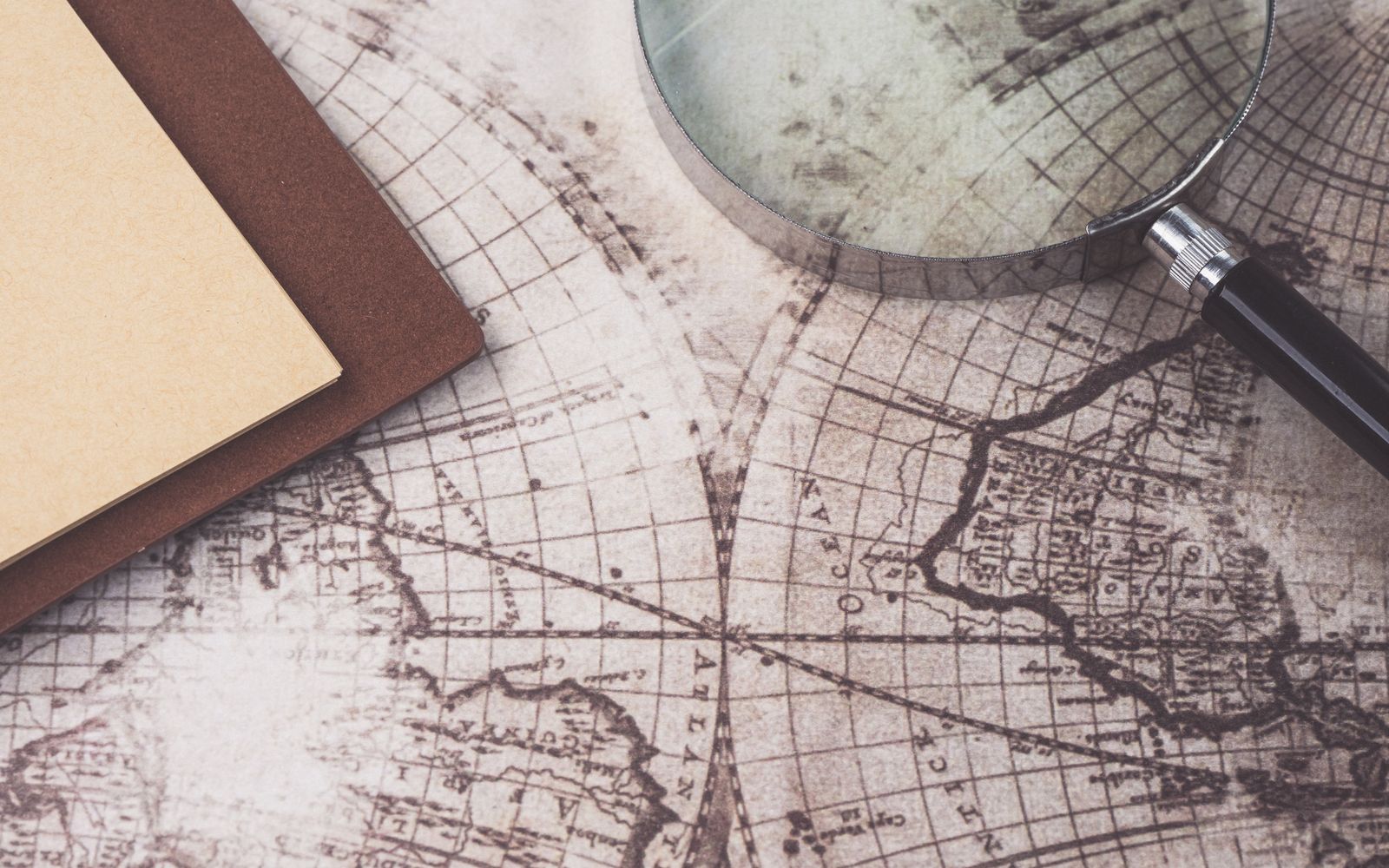 Magnifying glass and notebook resting on a world map, evoking global research