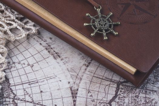 A vintage-style leather-bound journal with a nautical charm on an antique world map, evoking exploration.
