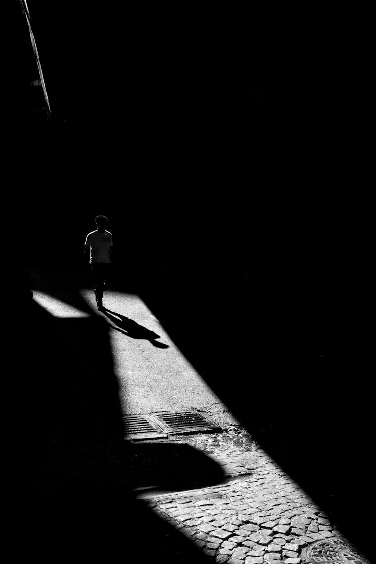 Man Walking On Cobblestone In Darkness