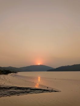 Stunning sunset over a calm waterfront in Thane, India, surrounded by serene hills and natural beauty.