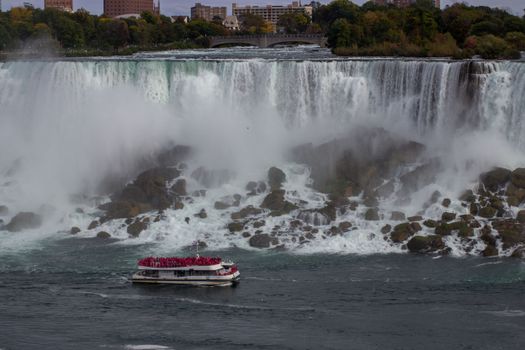 A boat navigates near the rushing waters of Niagara Falls, an iconic tourist destination.