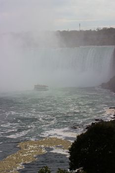 A breathtaking view of Niagara Falls shrouded in mist, featuring a tourist boat on the water.