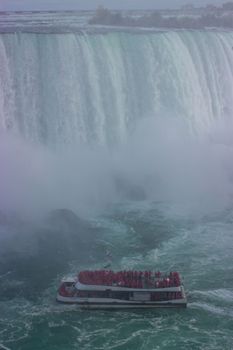 A tourist boat full of people approaches the majestic Niagara Falls in Canada.