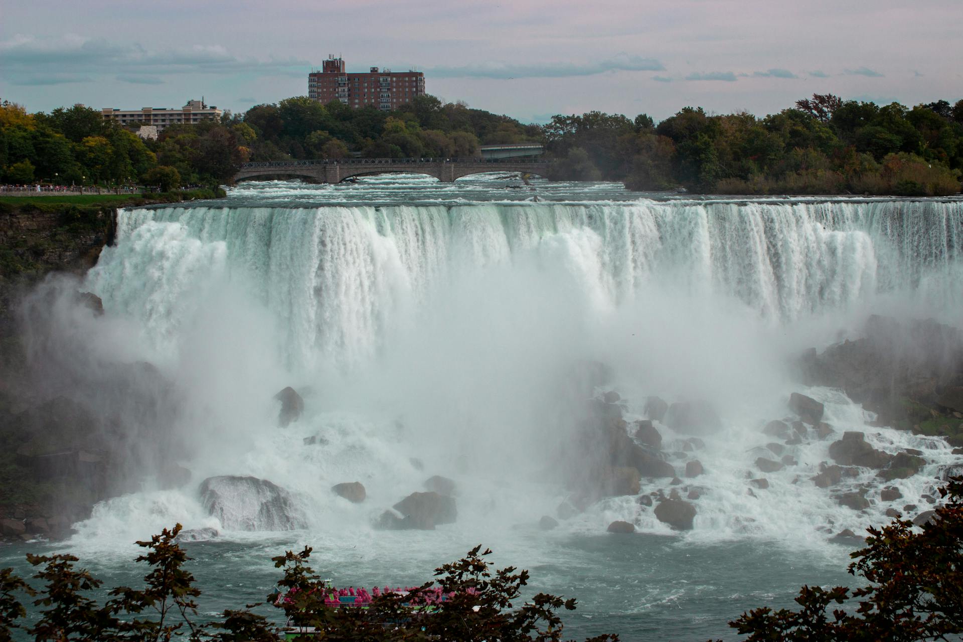 Majestic view of Niagara Falls cascading into the river below on a calm day.