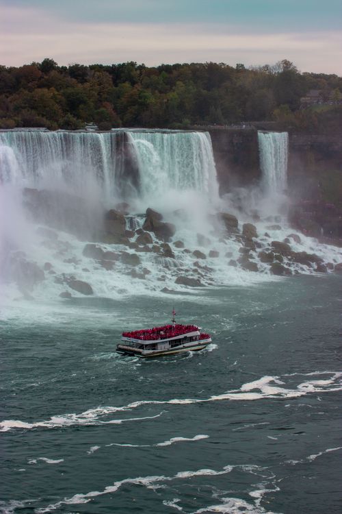Free Tourists enjoy a boat ride near Niagara Falls, capturing the powerful waterfall's beauty. Stock Photo