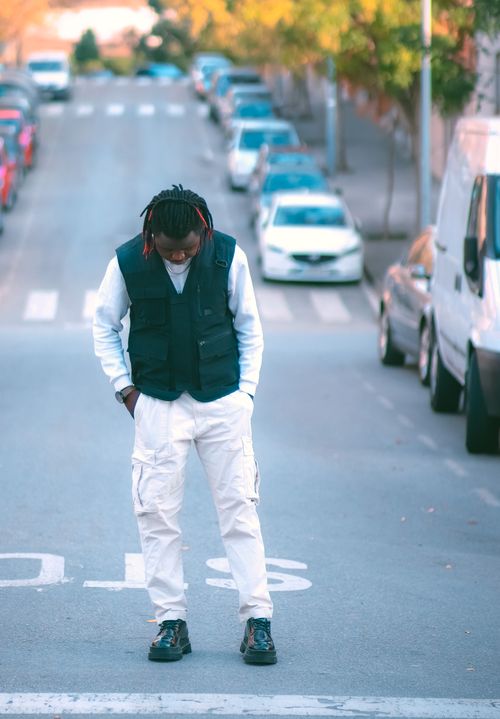 Free Fashionable young man in white pants and vest standing on a city street during the day. Stock Photo