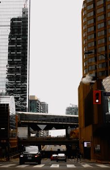 A view of a city street with cars and high-rise buildings on a cloudy day.