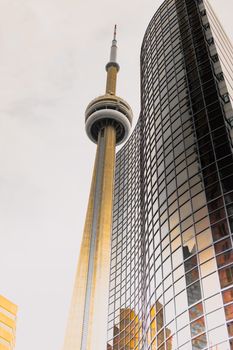 Low angle shot of CN Tower next to a reflective skyscraper in Toronto, capturing the iconic skyline.