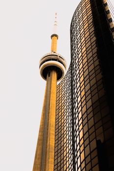 Stunning upward shot of CN Tower alongside modern Toronto skyscraper.