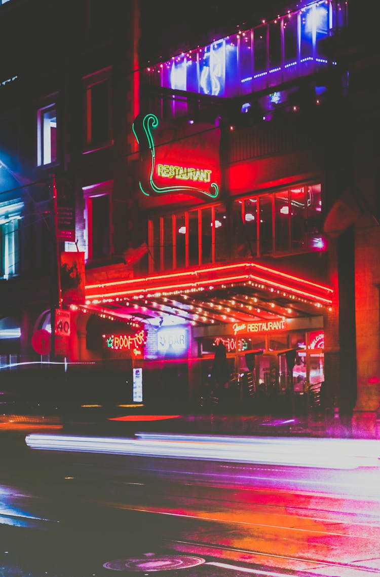 Long Exposure Photo Of Cars Passing By The Lighted Building