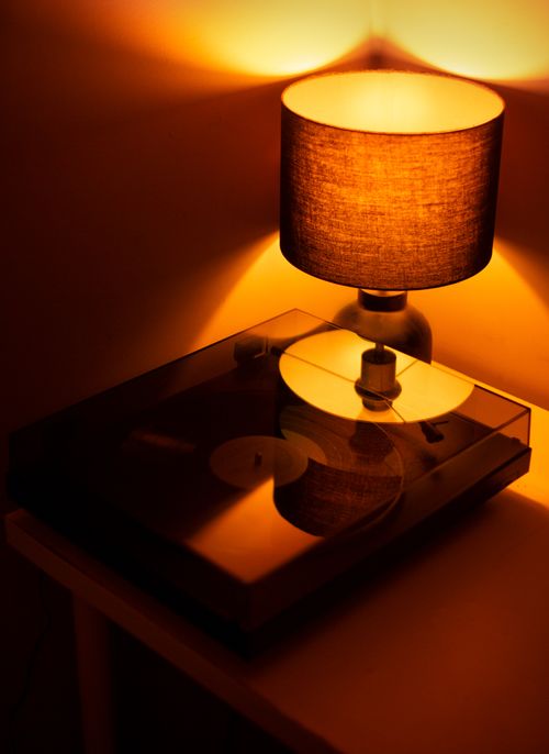 Free A warm, ambient still life featuring a lit lamp beside a turntable casting shadows. Stock Photo